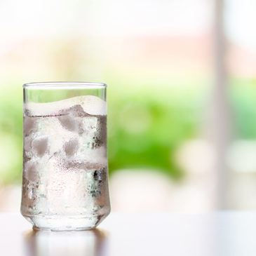 Das Bild zeigt ein Glas frisches Wasser mit Eiswürfel